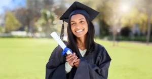smiling-graduate-gown-holding-a-diploma-tied-with-a-blue-ribbon1
